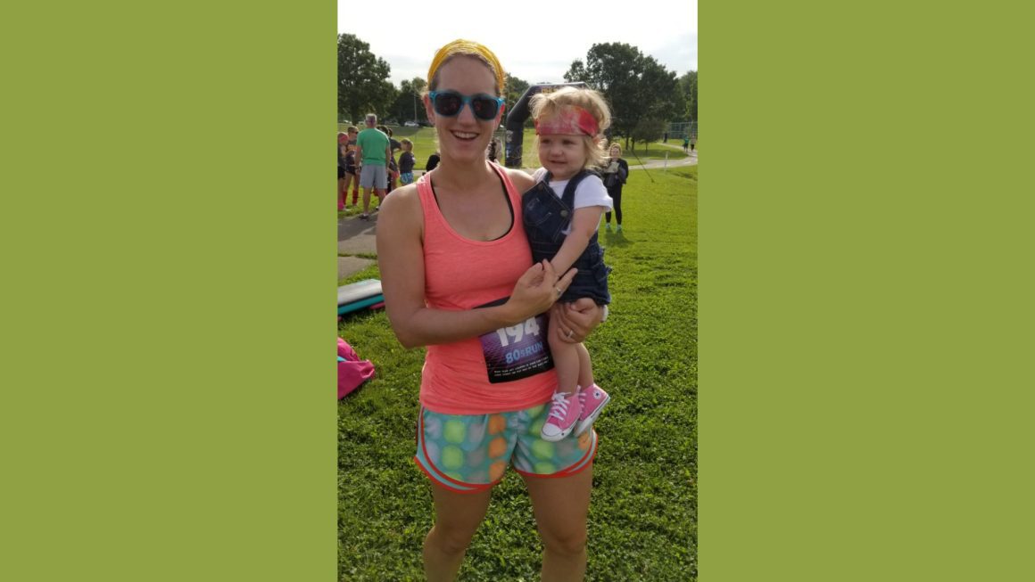 Tami holding her daughter Ada at a marathon