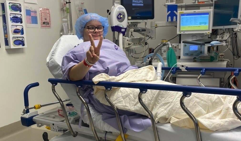 Madelyn throwing a peace sign from her hospital bed